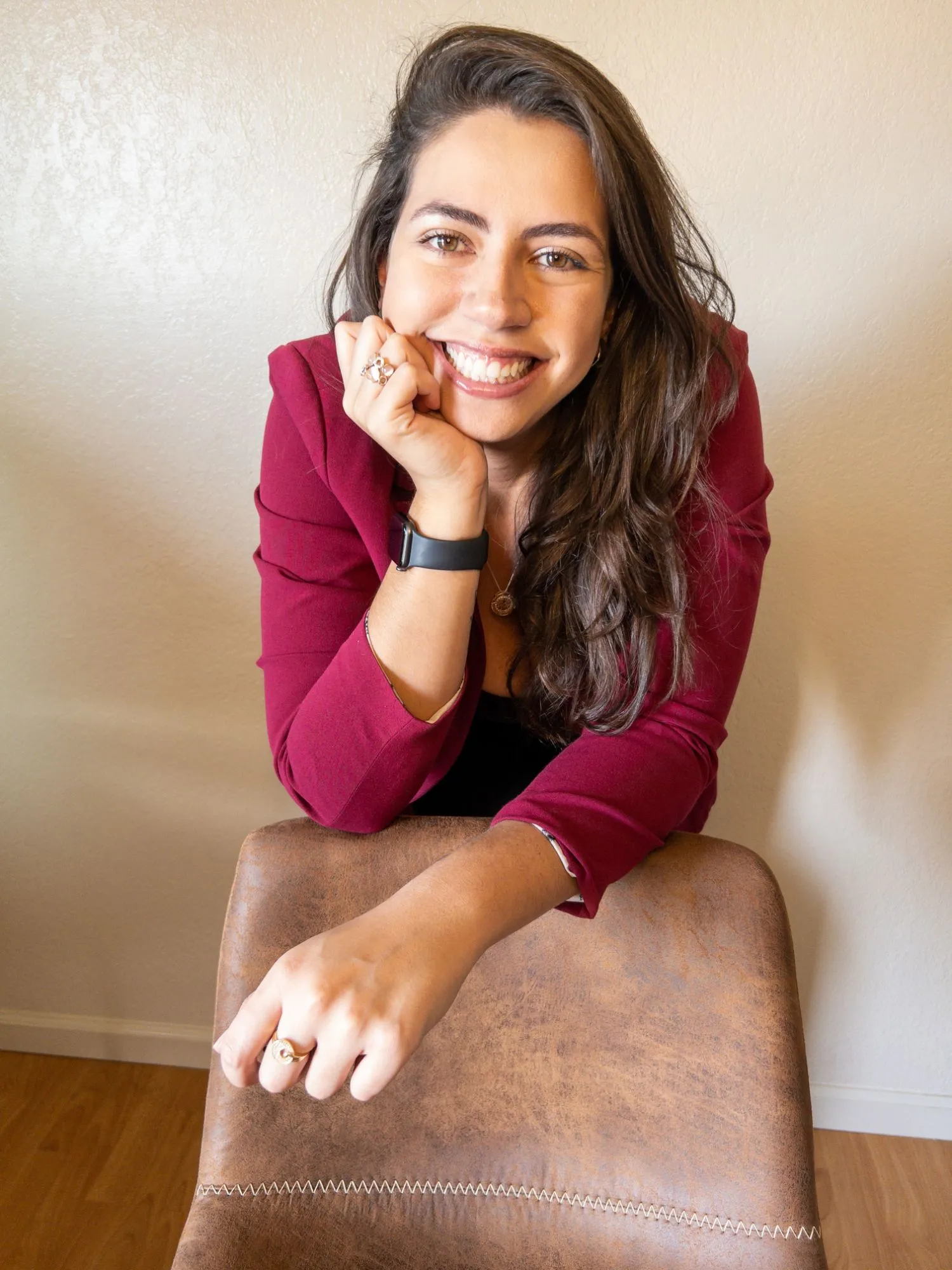 Bia Aguiar, founder of MantaB, smiling, leaning on the back of a chair